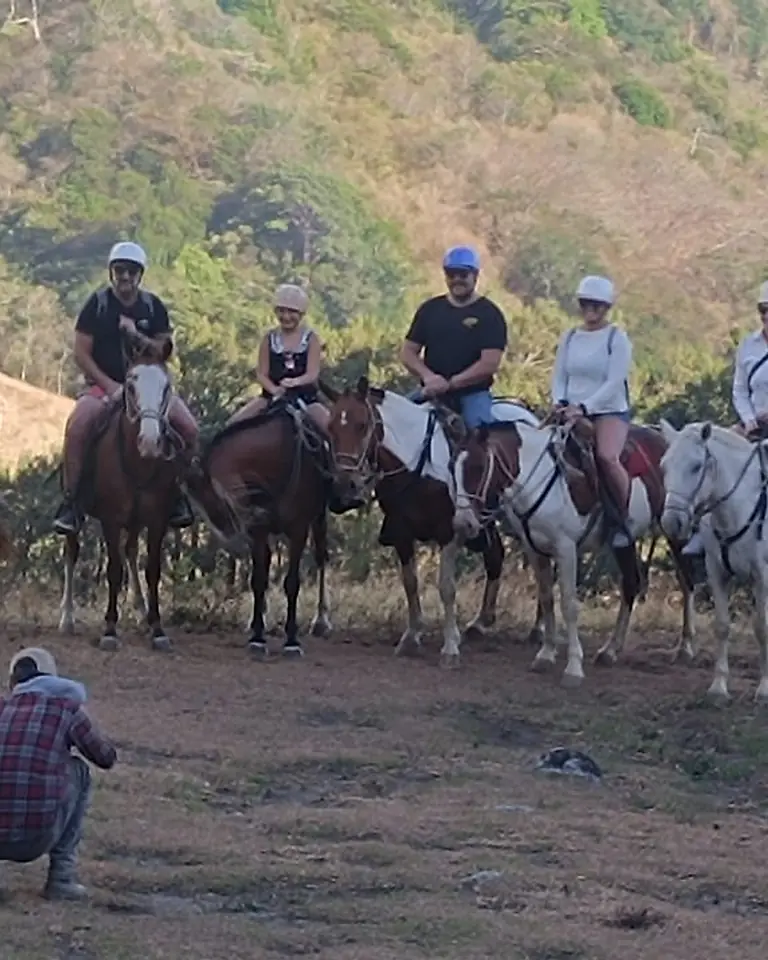 Grupo a caballo en una colina de Costa Rica, con cascos, frente a las montañas