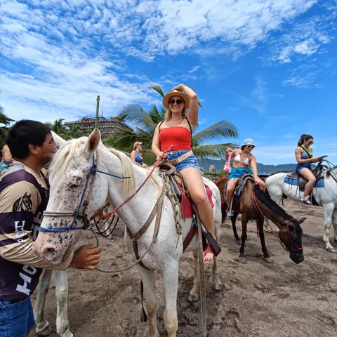 Jinete con sombrero sobre un caballo blanco en la playa