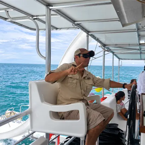 Guía a bordo del catamarán, con el mar detrás