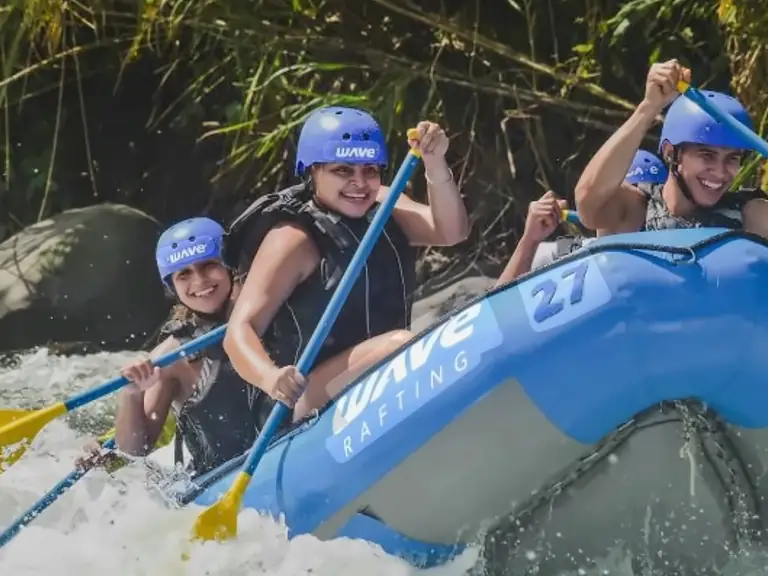 Grupo con casco remando en una balsa entre los rápidos
