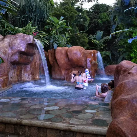 Bañistas bajo una cascada de agua termal