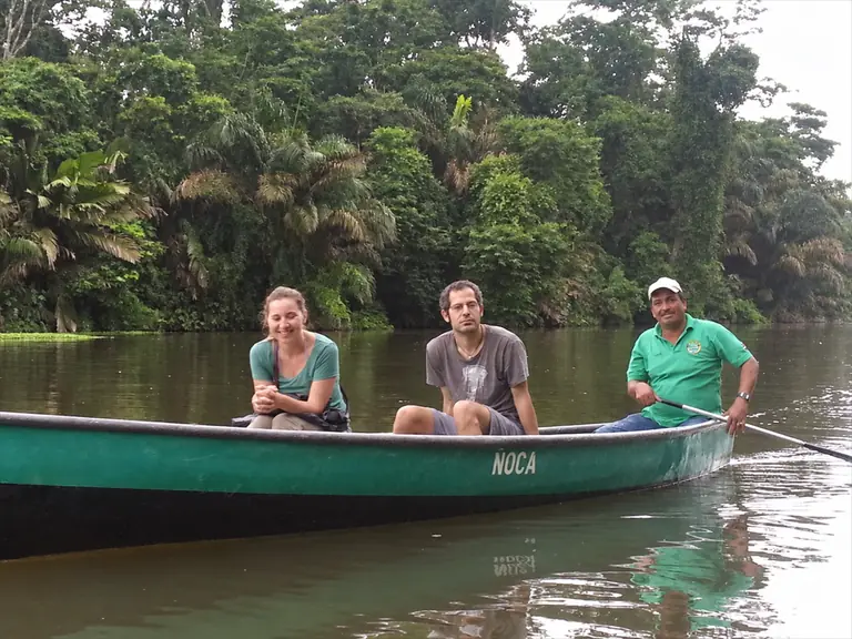 Tres visitantes en un bote por los canales de Tortuguero