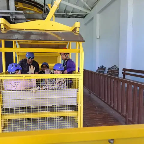 Visitantes con casco en la góndola amarilla del teleférico